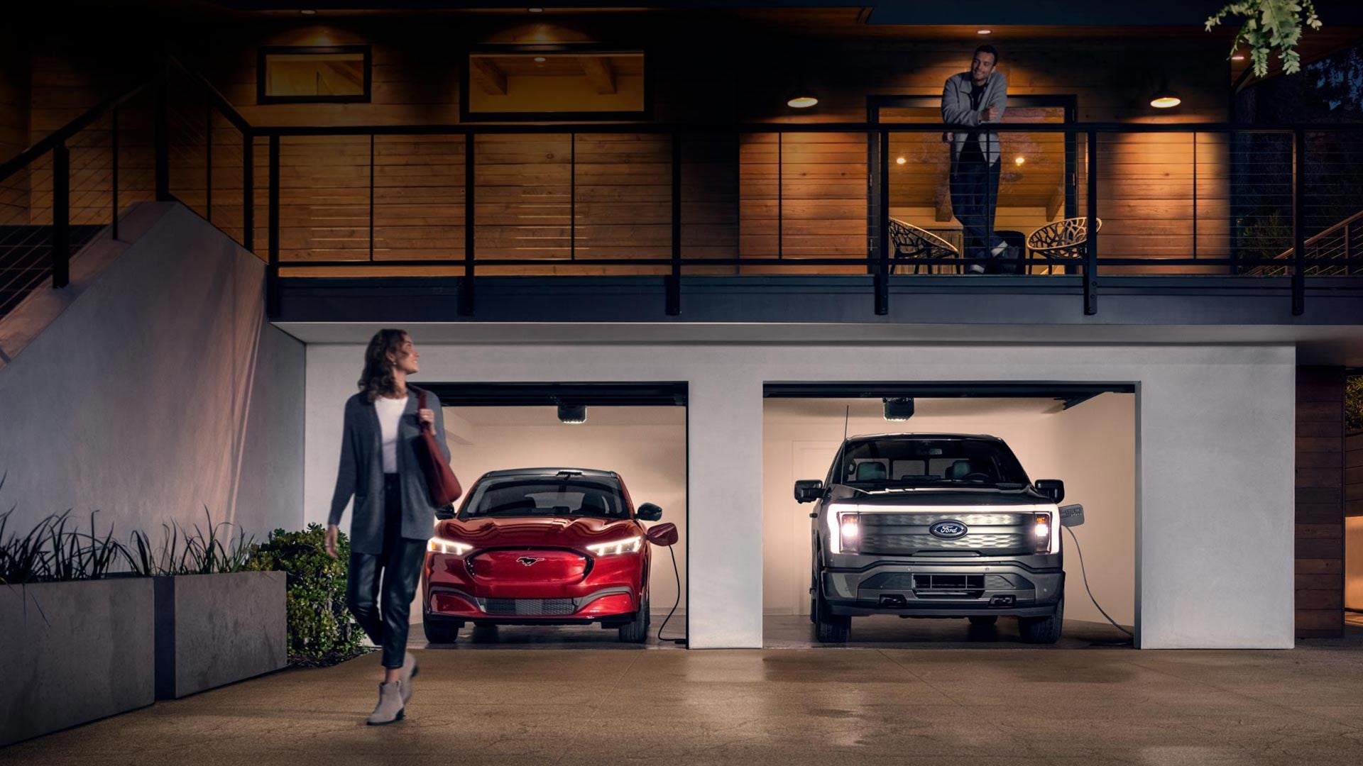 Woman walking out from home garage with a 2024 Mustang® Mach-E and Ford Lightning® truck in plugged-in and charging | Angela Krause Ford in Alpharetta GA
